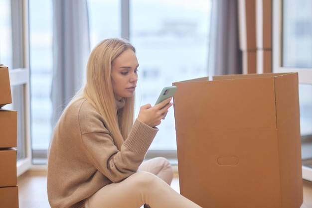 Young woman moving new place and repair concept happy young woman with many cardboard boxes sitting