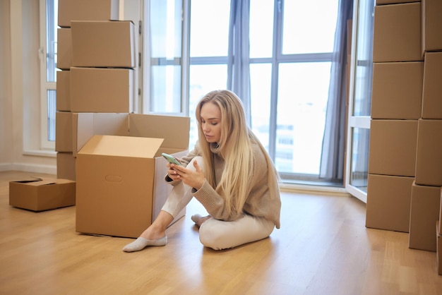 Young woman moving new place and repair concept happy young woman with many cardboard boxes sitting