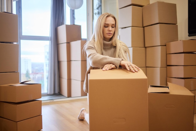 Young woman moving new place and repair concept happy young woman with many cardboard boxes sitting