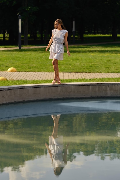 Young woman n dotted white sundress posing in the city park