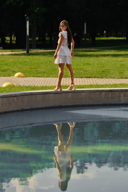 Young woman n dotted white sundress posing in the city park