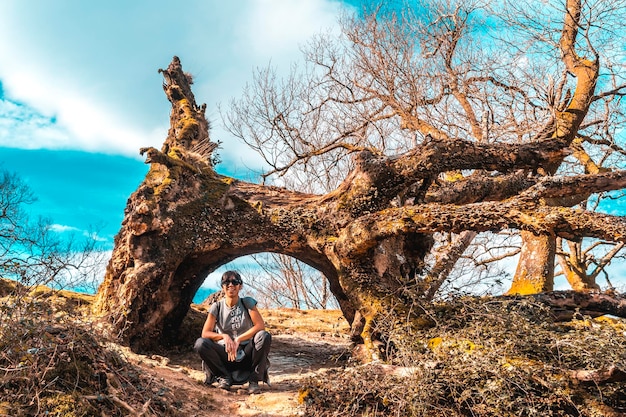 A young woman next to a natural tunnel of a tree on the path of Mount Adarra in Guipuzcoa