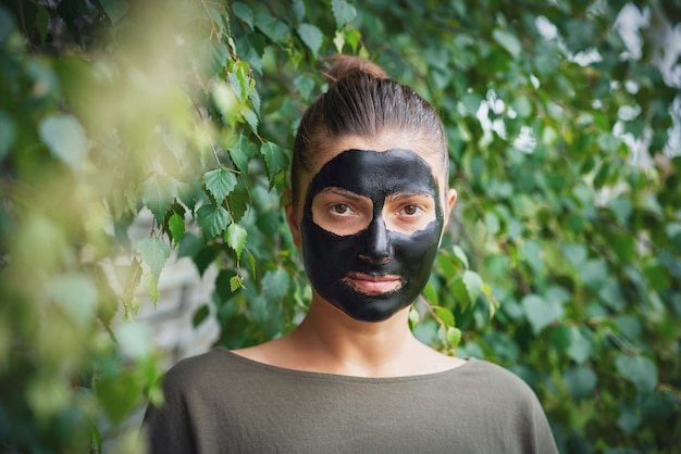 Young woman in nature with black mask on face