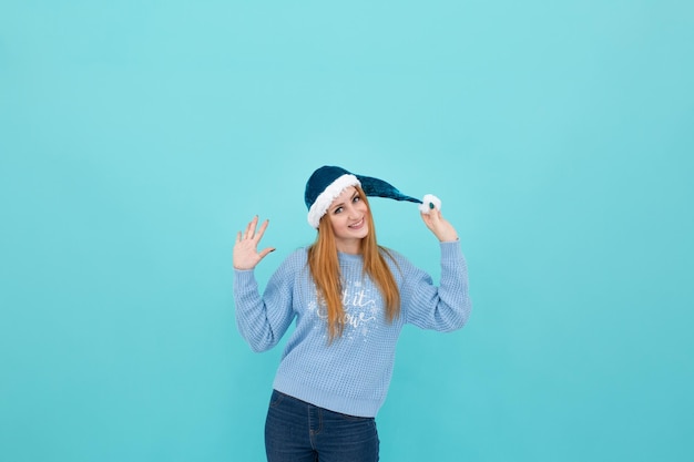 young woman in a New Year's hat on a blue background. woman hold a New Year's hat in her hands. Chri