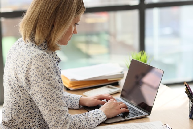 A young woman in the office is typing on a laptop keyboard a closeup overtime work entrepreneur