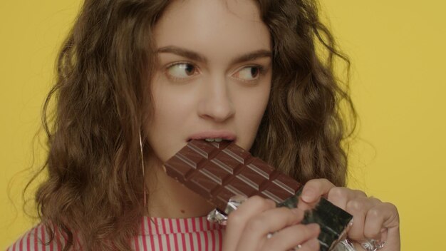 Photo young woman opening chocolate bar portrait of happy girl eating chocolate