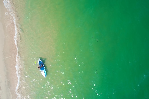 Young woman paddling on SUP board on the tropical beach Active summer vacations with paddle board