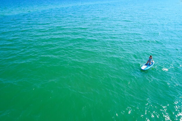 Young woman paddling on SUP board on the tropical beach Active summer vacations with paddle board