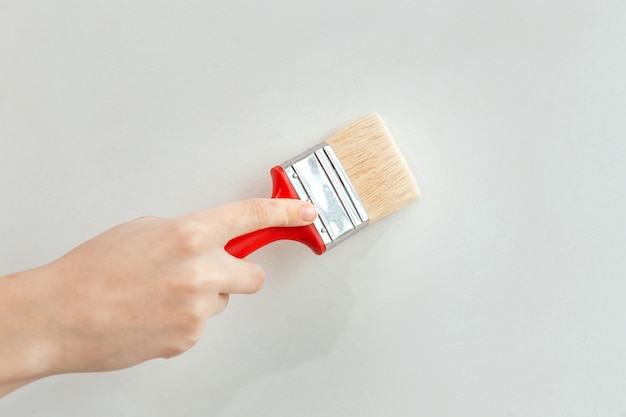 Young woman painting interior wall with paint brush