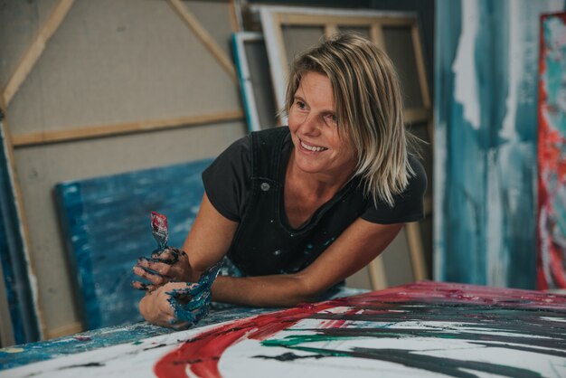 Young woman paints an abstract painting with her hands in her interior studio,