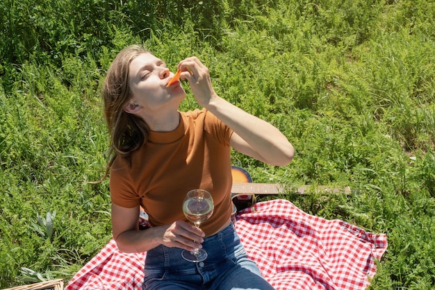 Young woman in park outside at sunny day enjoying summertime dreaming and drinking wine