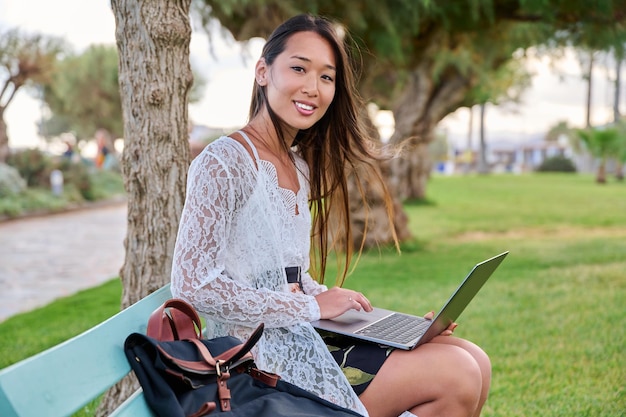 Young woman in the park with a laptop looking at the camera