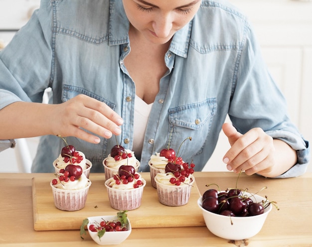 Young woman pastry chef decorates cupcakes