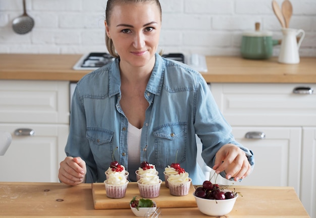 Young woman pastry chef decorates cupcakes