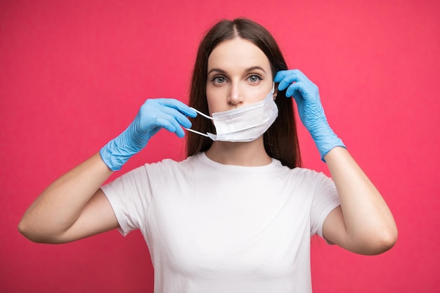 Young woman patient puts on medical mask in protective surgical sterile gloves on her arm