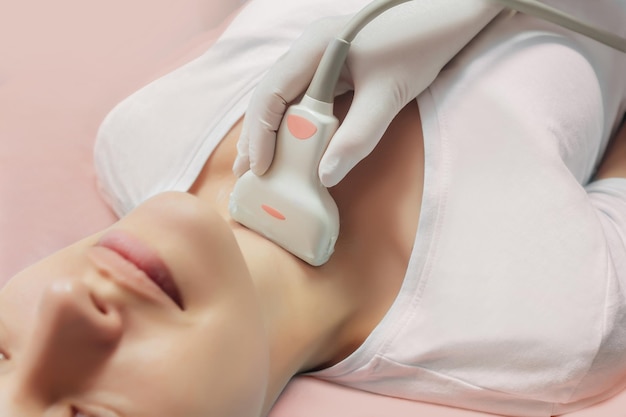 Young woman patient during the ultrasound examination of a thyroid lying on the couch in medical office