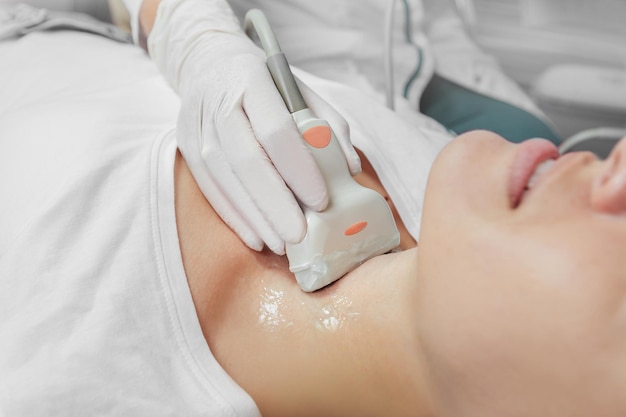 Young woman patient during the ultrasound examination of a thyroid lying on the couch in medical office