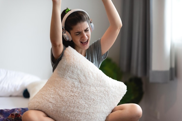 Young woman person wearing earphone or headphone to relaxing with song on the bed in bedroom at home concept of happy sound listen lifestyle in cozy audio feeling