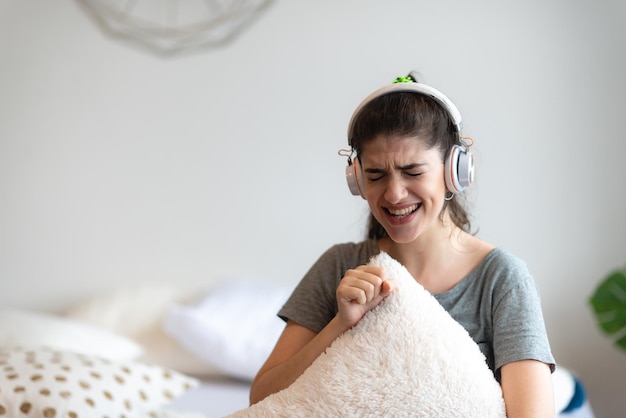 Young woman person wearing earphone or headphone to relaxing with song on the bed in bedroom at home concept of happy sound listen lifestyle in cozy audio feeling