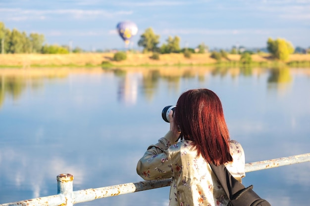 Young woman photographing a hot air balloon landing