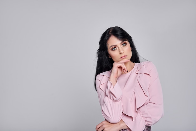 young woman in pink clothes. Girl posing on a gray wall.