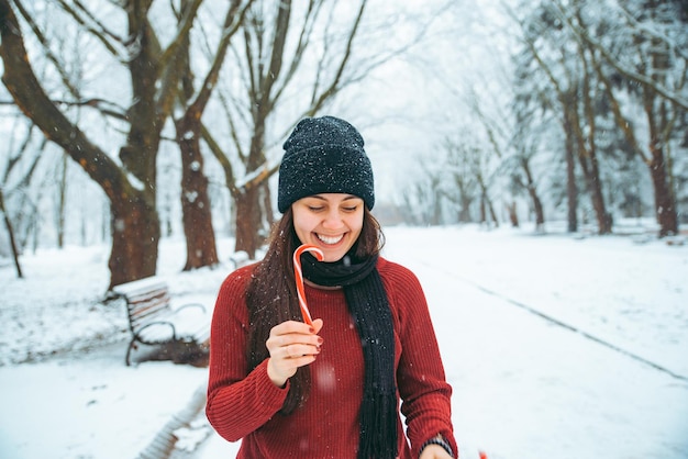 Young woman play in snowed city park christmas candies