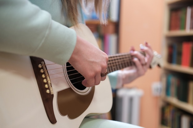 Young woman playing acoustic guitar. close-up without face