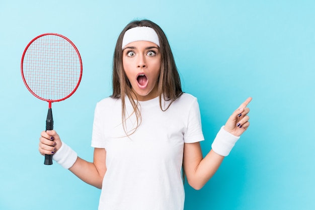 Young woman playing badminton isolated pointing to the side