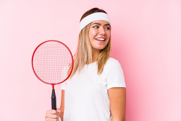 Young woman playing badminton looks aside smiling, cheerful and pleasant.