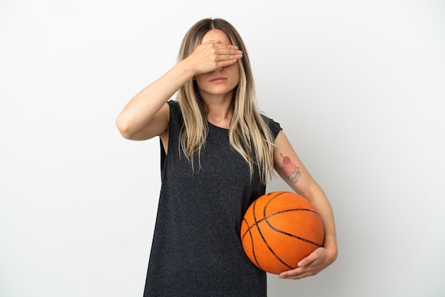 Young woman playing basketball over isolated white wall covering eyes by hands. Do not want to see something