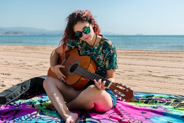 Young woman playing guitar on the beach