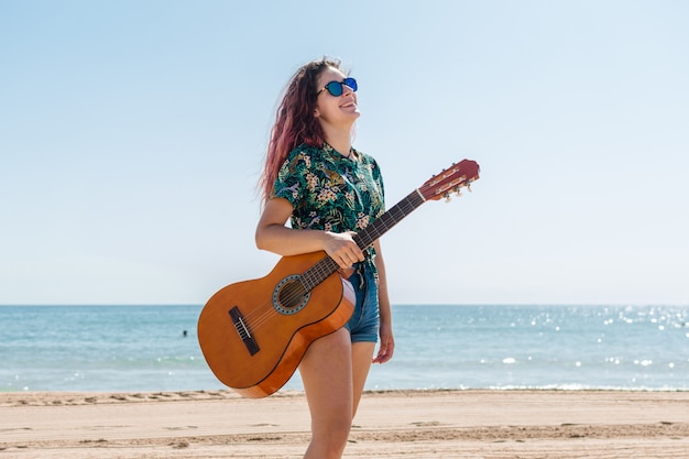 Young woman playing guitar on the beach