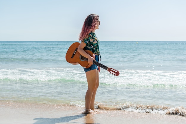 Young woman playing guitar on the beach