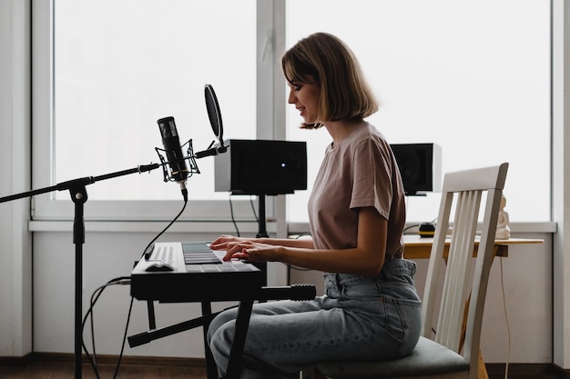 Young woman playing piano and singing a song at homestudio