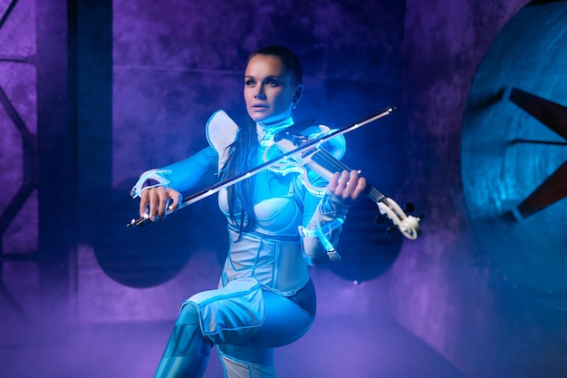 Young woman playing violin solo on stage illuminated with neon light