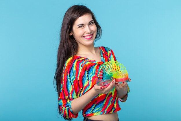 young woman playing with a slinky on blue wall