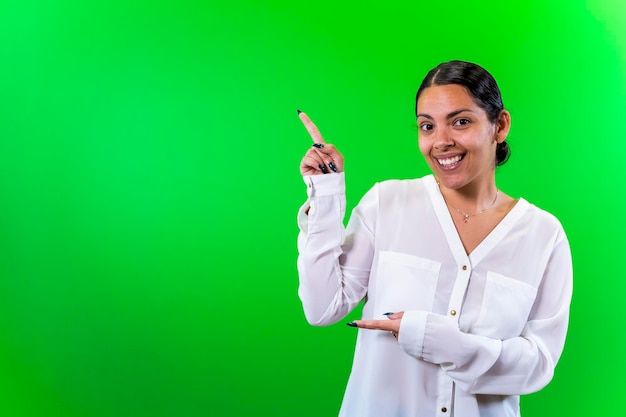 Young woman pointing side green background