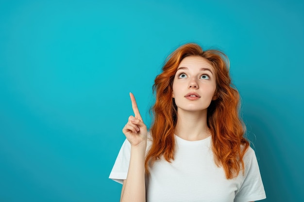 Photo young woman pointing up in tshirt and looking curious