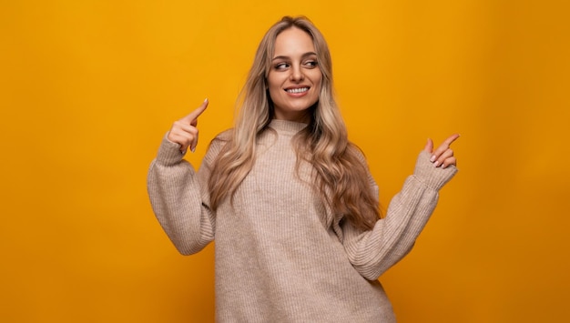 Young woman pointing with her hands at the wall over isolated background