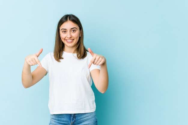 Young woman points down with fingers, positive feeling