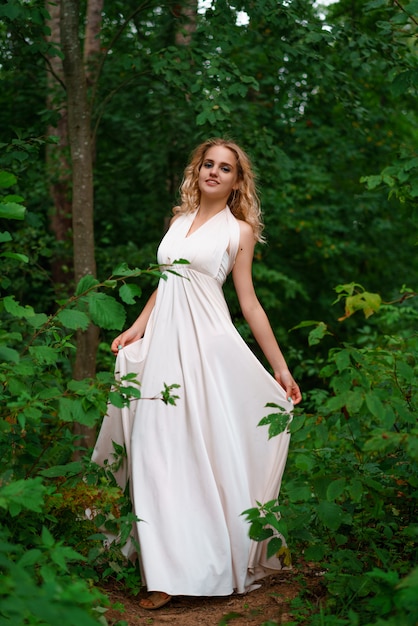 Young woman poses in a pink dress in the forest