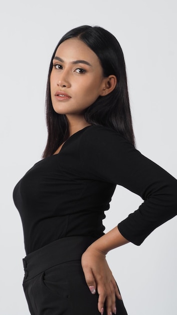 Young woman posing in black shirt and pants in the studio on white background