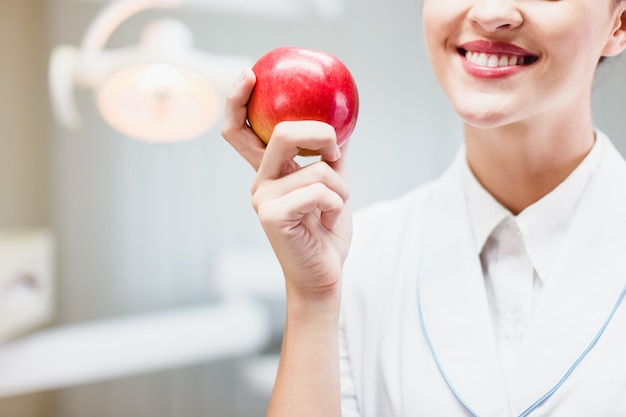 Young woman posing doctor in a dentist's office with an apple