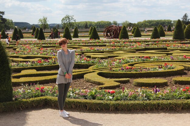 Young woman posing near the Parterre du Midi garden in the Palace of Versaille