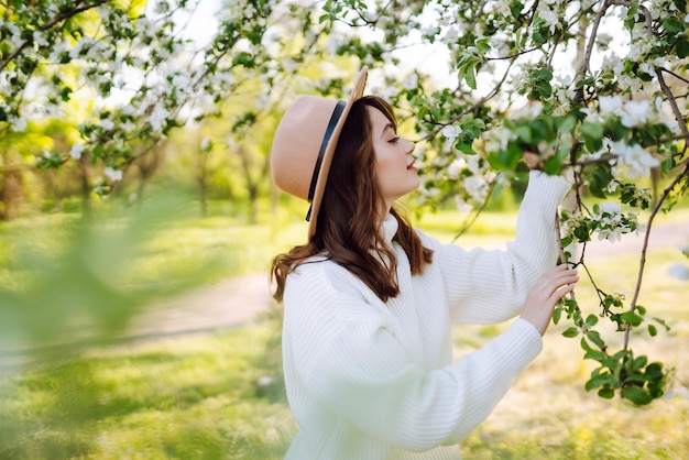 Young woman posing in spring blossom flowers in blooming garden Female beauty fashion