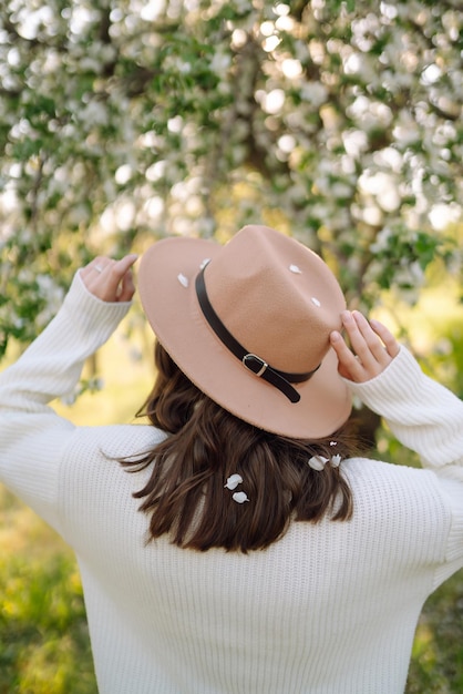 Young woman posing in spring blossom flowers in blooming garden Female beauty fashion