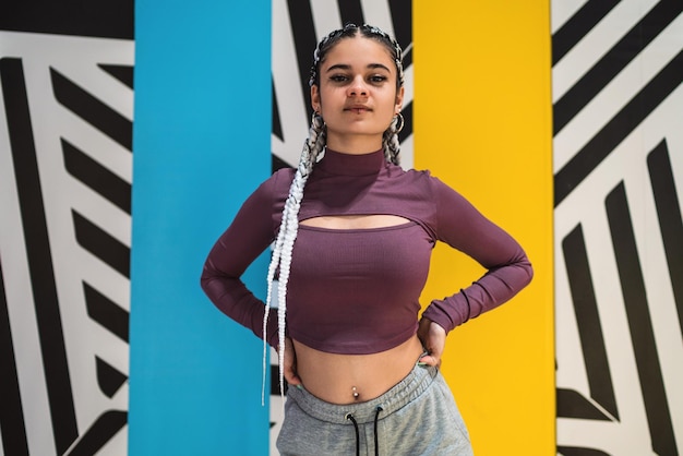 Young woman posing with handa on her waist against an abstract wall