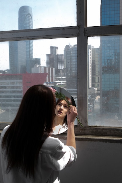 Photo young woman posing with mirror inside building next to window