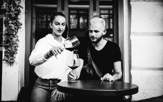 Photo young woman pouring wine in glass at cafe