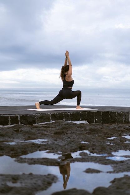 Young woman practice yoga on a beautiful beach at sunrise. Blue sky, ocean, waves, proximity to nature, unity with nature.